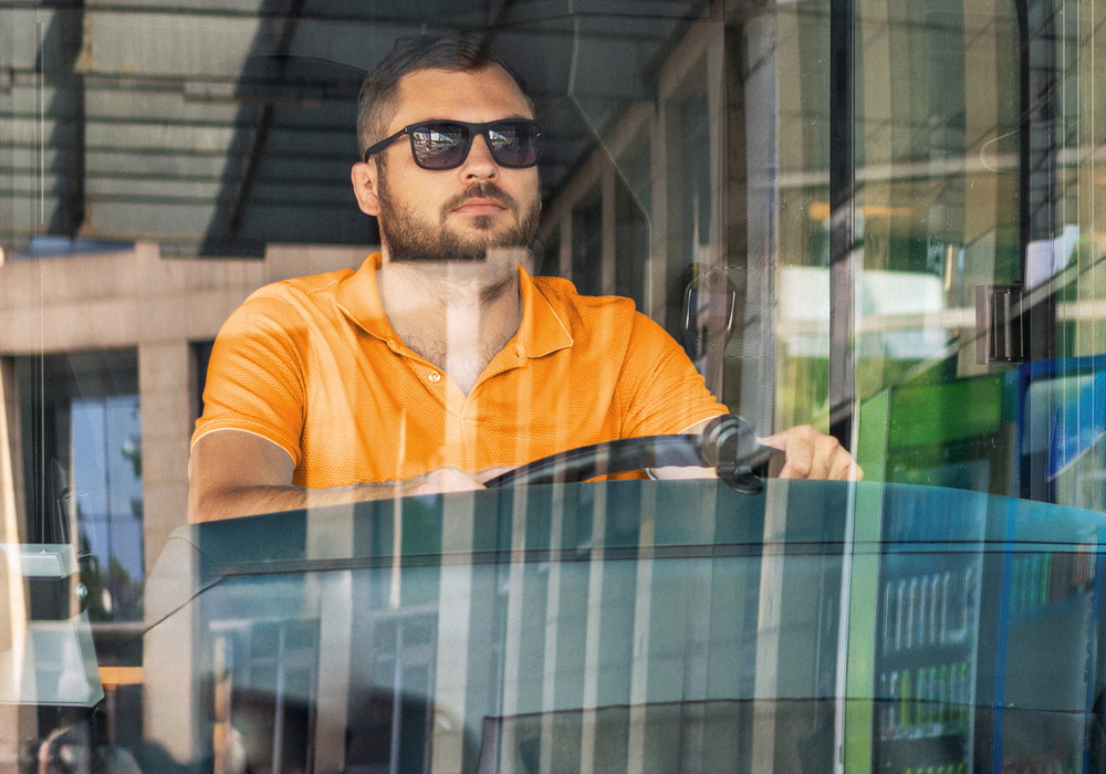 Ein bärtiger Mann mit Sonnenbrille fährt den Bus.