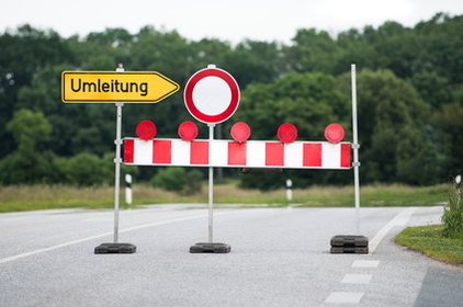 Straße auf der verschiedene Verkehrsschilder stehen u.a. ein Umleitungsschild und eine Absperrbake sowie dem Schild "“Einfahrt verboten".