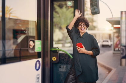 Frau steigt glücklich in Bus ein.