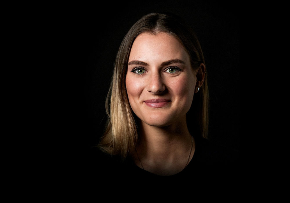 Gesicht einer lächelnden jungen Frau auf schwarzem Hintergrund