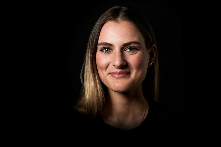 Gesicht einer lächelnden jungen Frau auf schwarzem Hintergrund
