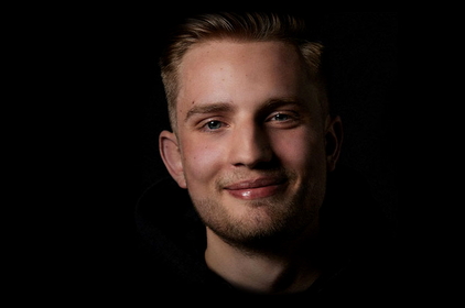 Foto eines lächelnden Azubis auf schwarzem Hintergrund.
