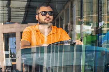 Ein bärtiger Mann mit Sonnenbrille fährt den Bus.