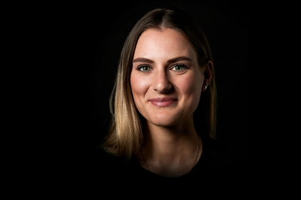 Gesicht einer lächelnden jungen Frau auf schwarzem Hintergrund