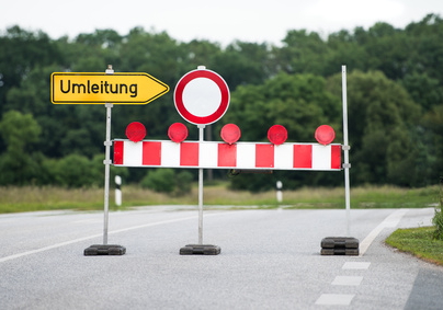Straße auf der verschiedene Verkehrsschilder stehen u.a. ein Umleitungsschild und eine Absperrbake sowie dem Schild "“Einfahrt verboten".