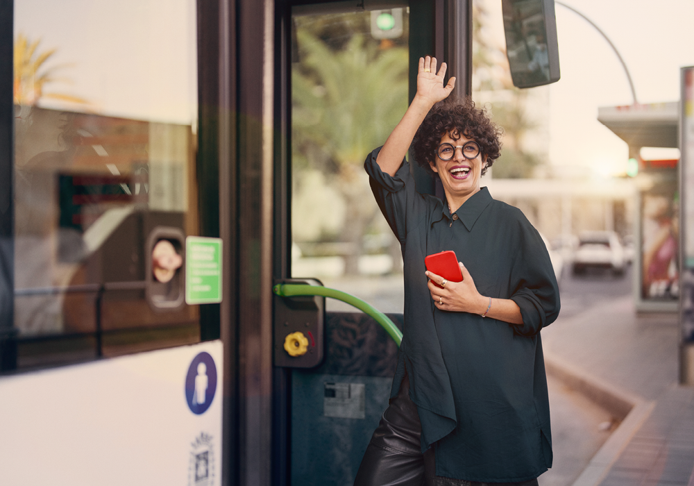 Frau steigt glücklich in Bus ein.